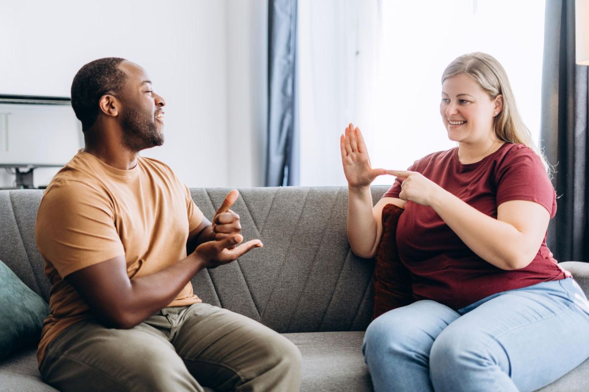 Two friends on a sofa signing to each other