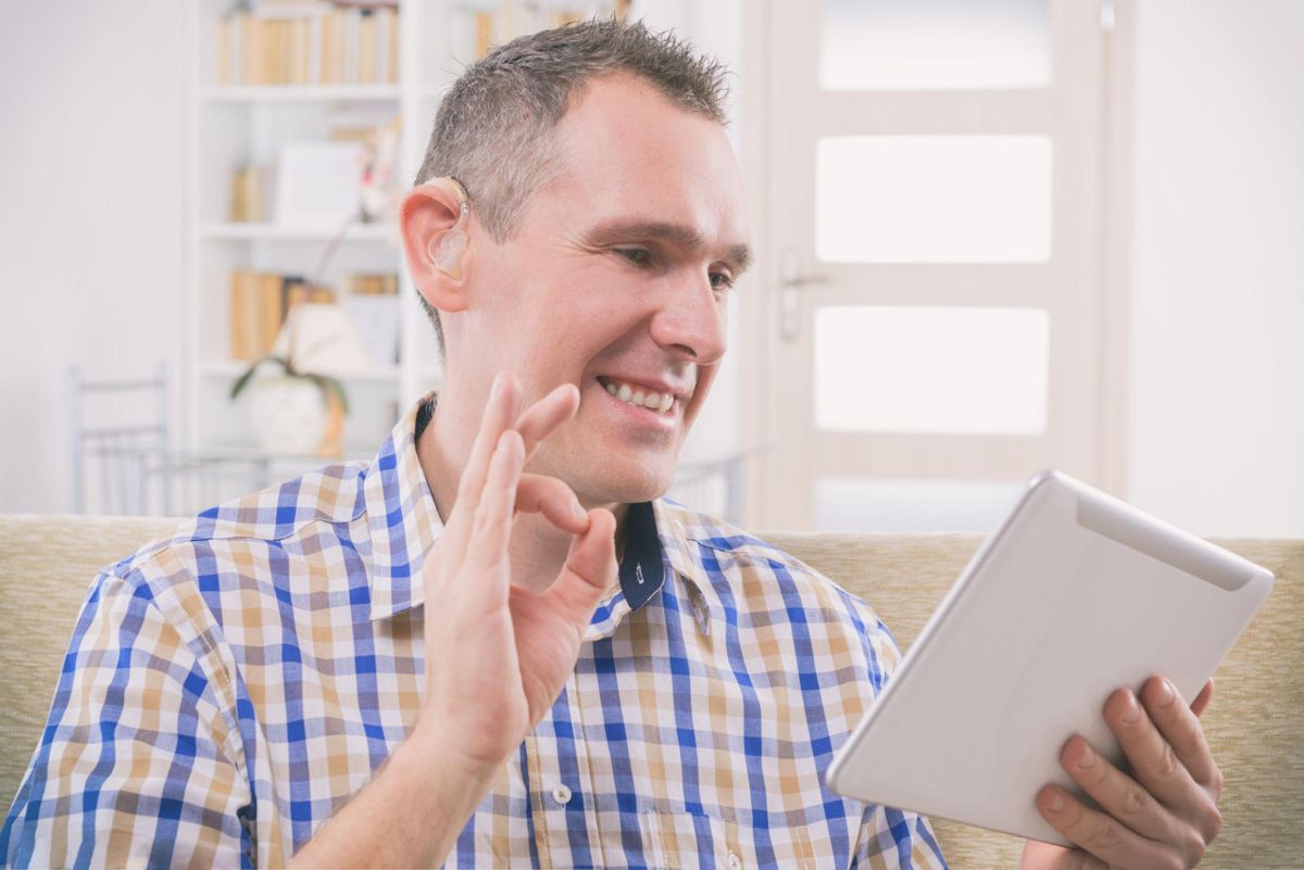 A man signing to someone on a tablet video call